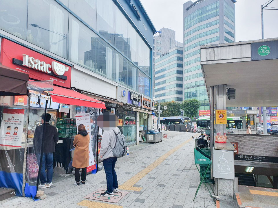 Isaac Toast & Coffee 228 2호선 금연구역 금연구역 편의시설 이용안내 metro 서울대입구 (출입구 영문·부기) 80 (원경 상가 간판 다수 · 이삭 벽 메뉴판 · 부동산 간판)